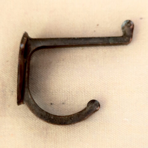 Vintage metal hat and coat hook mounted on wall with rustic finish