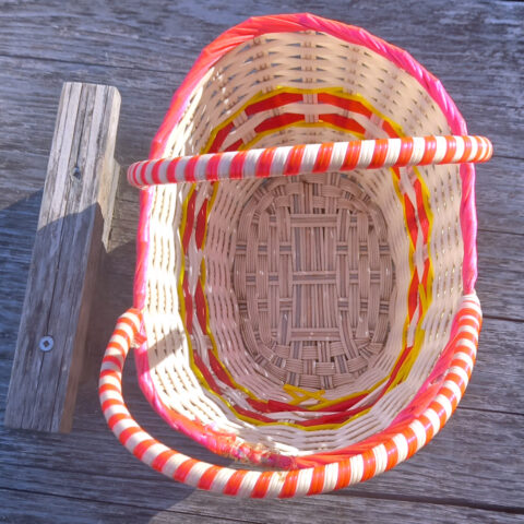 Small 1960s vintage plastic woven basket with colorful retro pattern and sturdy handles