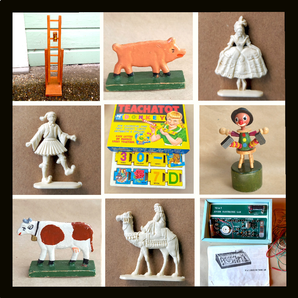 Assorted vintage toys including retro dolls, tin cars, and classic wind-up figures displayed on a wooden surface