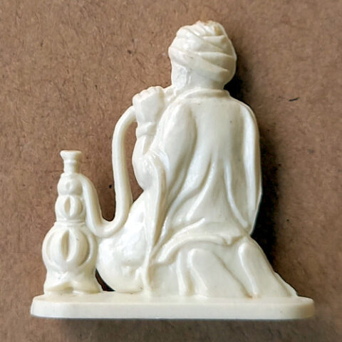 Vintage margarine figurine of a man wearing a turban smoking a hookah (shisha) close-up