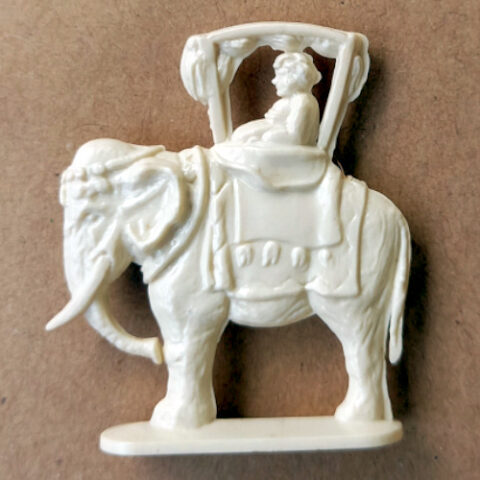 Vintage margarine figurine of a person sitting in a howdah on an elephant with detailed retro craftsmanship