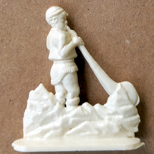 Vintage margarine figurine of an alphorn player in traditional folklore costume holding a long alpine horn