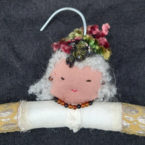 Old wooden clothes hanger transformed into a fun hanger with a sewn face and arms