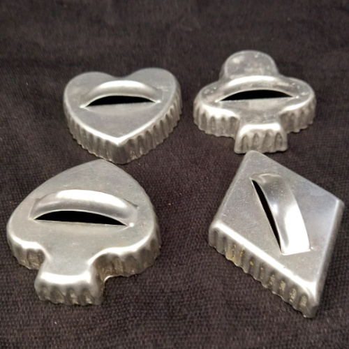 Four vintage aluminium cookie cutters with handles in spades, hearts, diamonds and clubs shapes