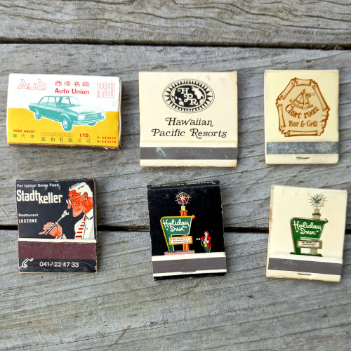 Six vintage advertising matchbooks with original matches featuring colorful retro business advertisements.