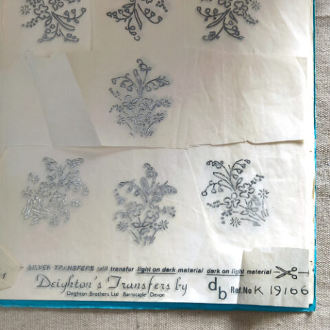 Vintage hand embroidery iron-on transfer sheet with assorted floral patterns, some transfers already used