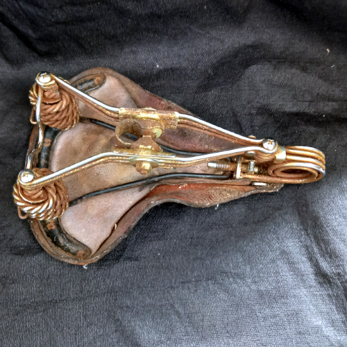 Well-worn vintage Brooks B33 leather bicycle saddle made in England with original sprung steel frame.