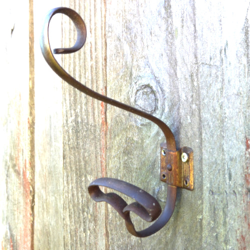 Antique wrought iron wall hook with curled scroll design and aged metal finish