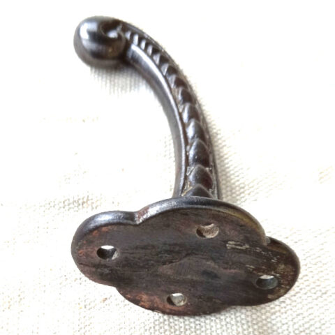 Vintage cast iron wall hook with curled tip and raised decorative detailing
