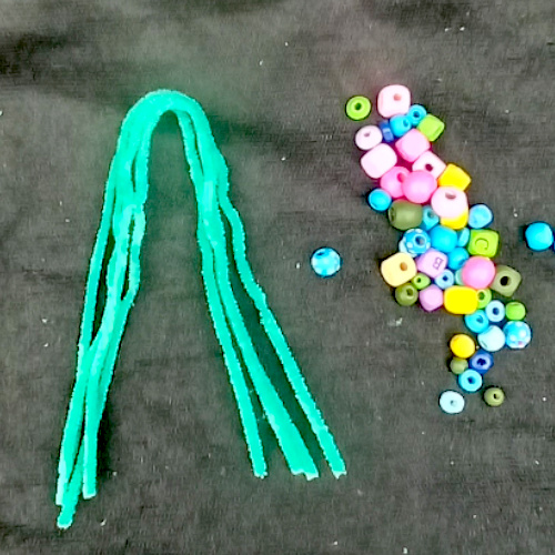 Handmade pipe cleaner tree decorated with wooden beads, with twisted branches and a base that stands upright.