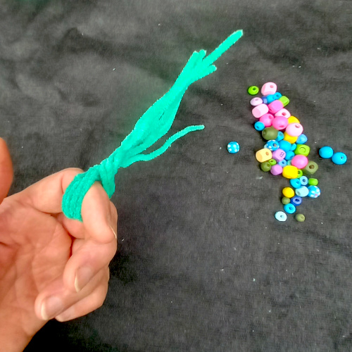 Handmade pipe cleaner tree decorated with wooden beads, with twisted branches and a base that stands upright.