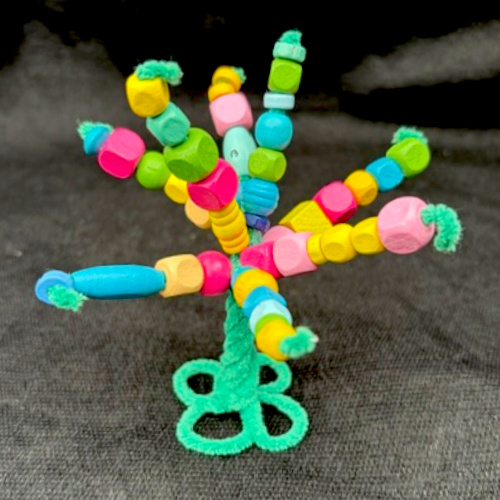 Handmade pipe cleaner tree decorated with wooden beads, with twisted branches and a base that stands upright.